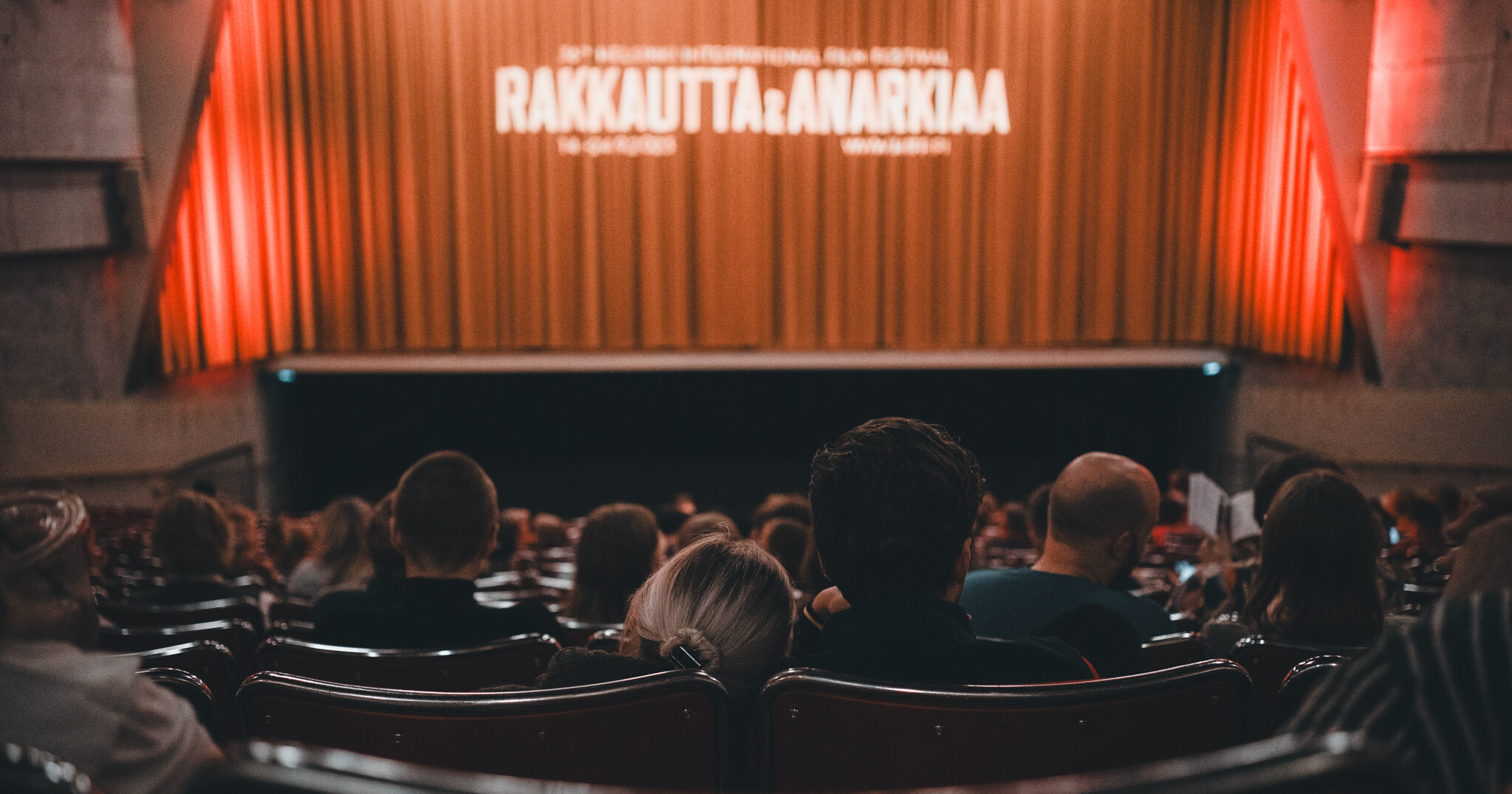 Yleisöä Bio Rexissa. Kaksikko yleisössä nojailee toisiinsa.